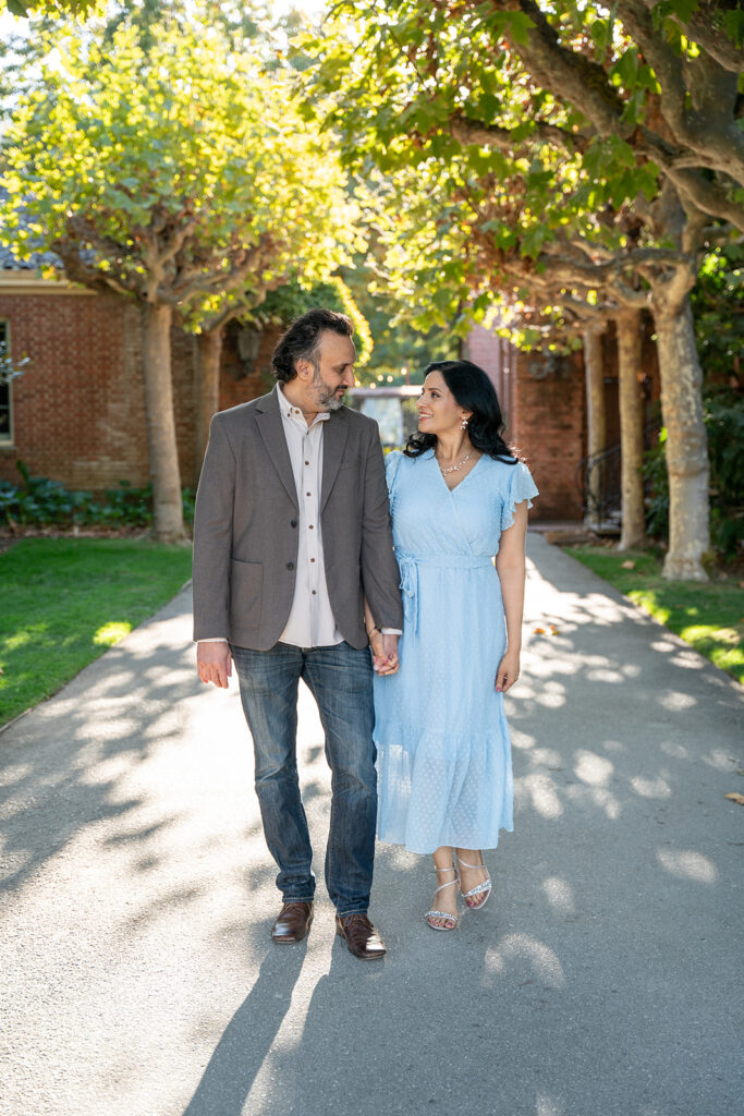 Indian couple standing under the tree arches in California's Filoli Gardens walking and smiling at each other