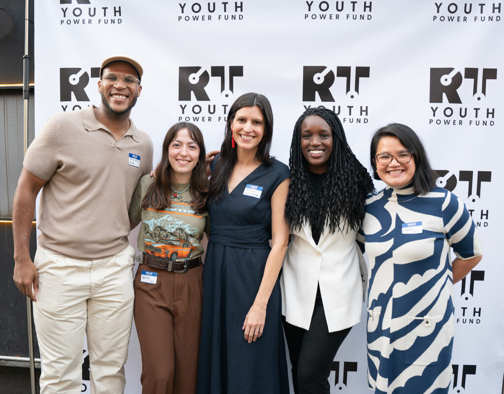 Youth Power Fund group photo with a mix race of individuals in front of their banner smiling directly at the camera