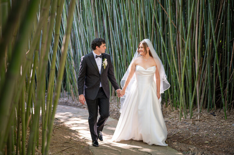 Wedding coupler walking hand in head through the bamboo trail at Celebrate at Snug Harbor in Staten Island, New York