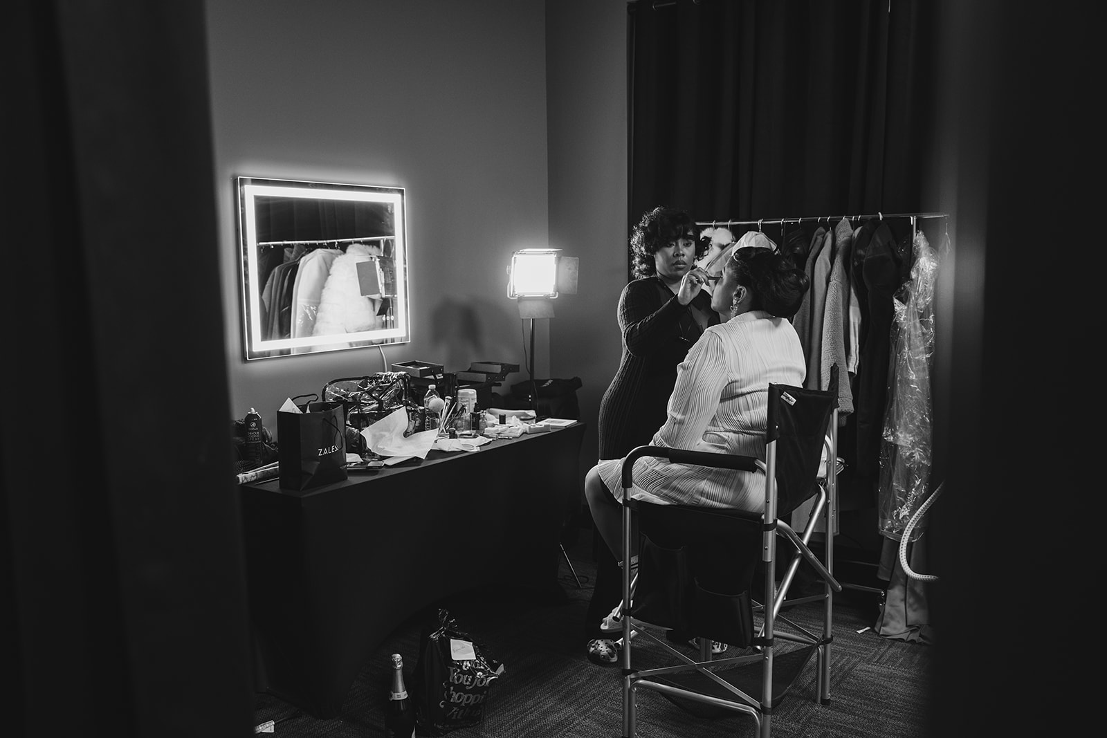 Black makeup artist applying makeup to her black bride client in a chair