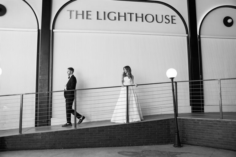 Black and white photo of a bride in her white gown looking back at the groom as he walks past her at The Lighthouse venue in New York City located at Chelsea Piers